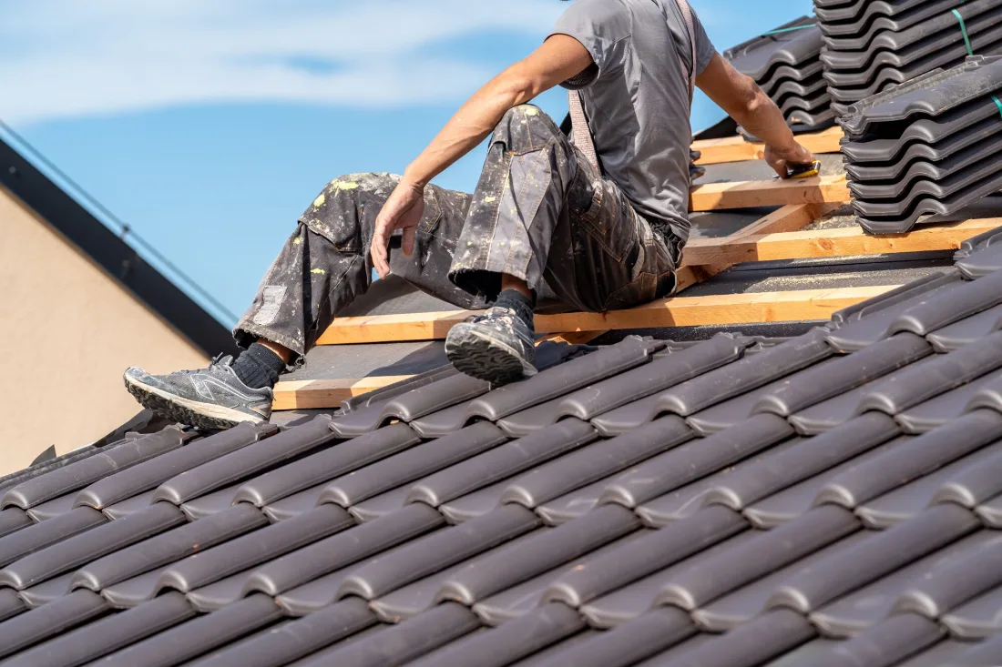 Roofer laying new concrete roof tiles on battens