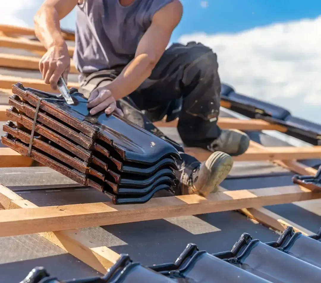 Roofer handling a stack of new roof tiles